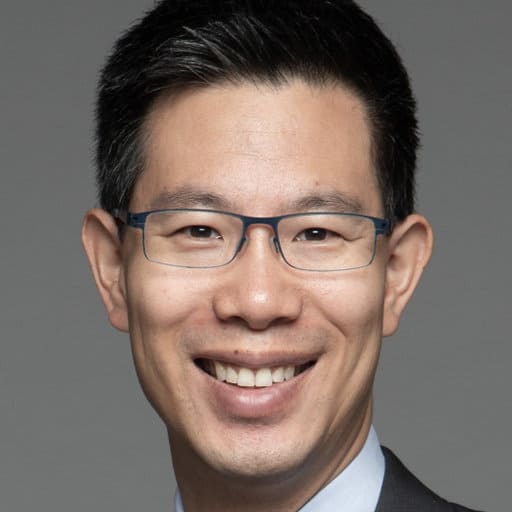 Dr. Dennis-Hwang, a man with short, thick black hair wearing rectangular blue glasses.
