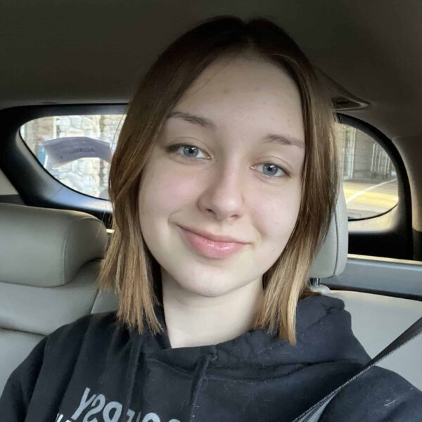 Staci H, a teenager with shoulder-length blonde hair and blue eyes wearing a black hoodie