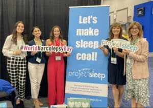 Group of women pose around Project Sleep booth at SLEEP 2023.